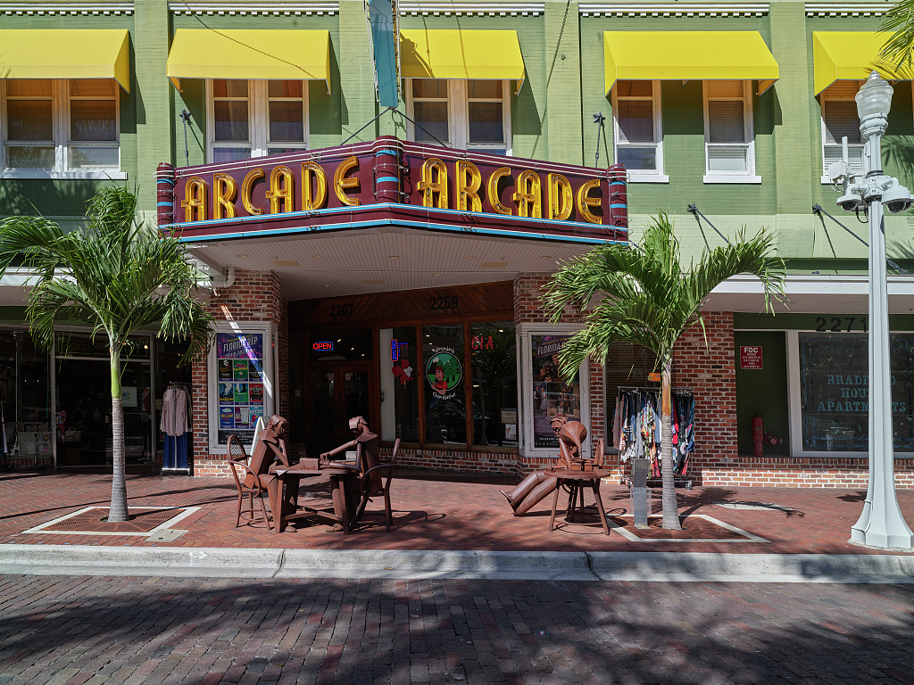 The Arcade Theatre and brick-paved First Street in downtown Fort Myers, Florida, with palms, awnings, and street furniture